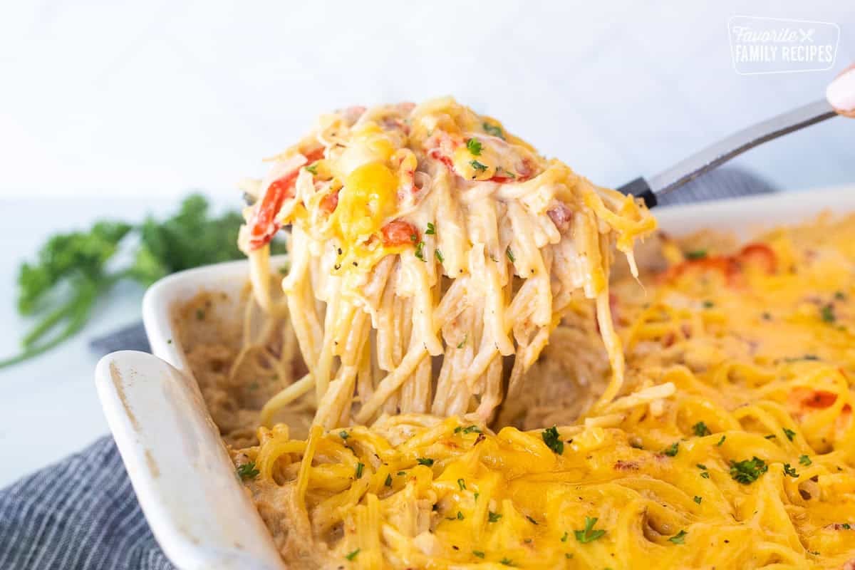 Lifting a scoop of chicken spaghetti casserole from dish.