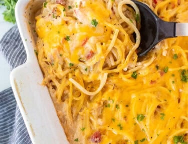 Spoon in casserole dish of chicken spaghetti casserole.