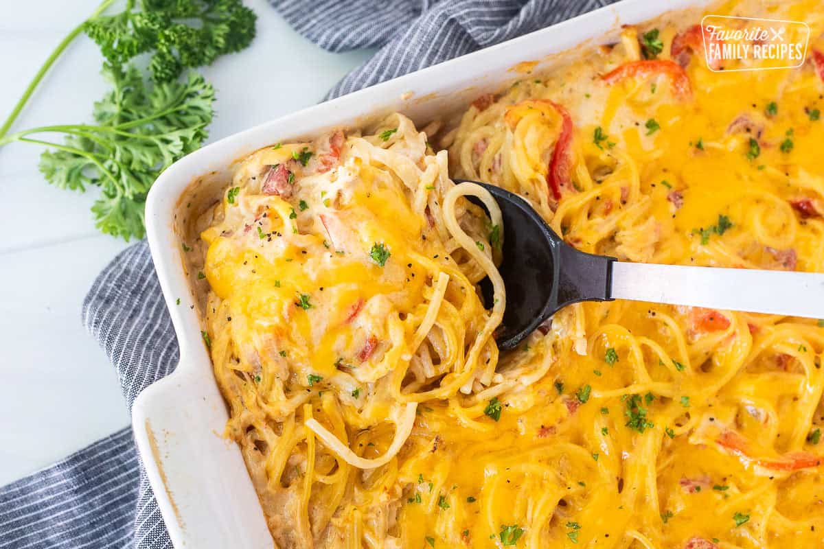 Spoon in casserole dish of chicken spaghetti casserole.