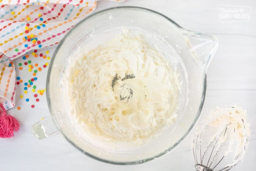 Glass mixing bowl with whipped butter and powdered sugar. Whisk attachment on the side.