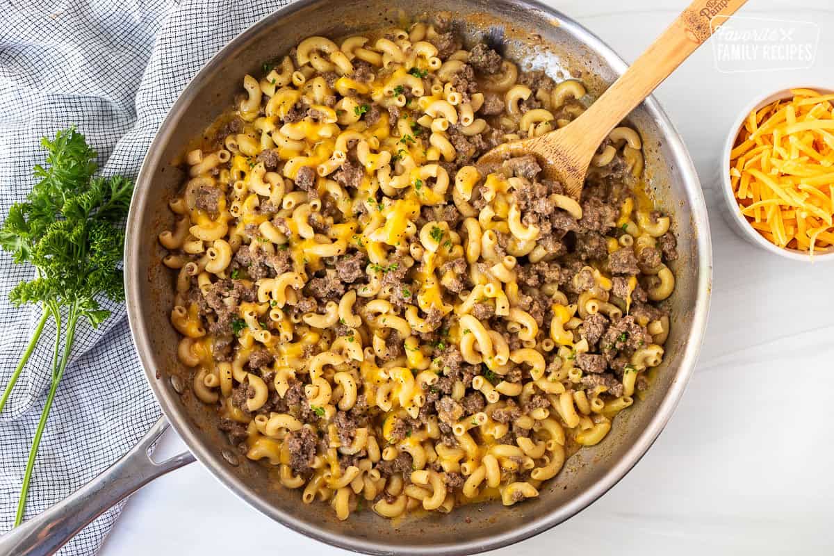 Skillet of homemade hamburger helper with a wooden spoon.