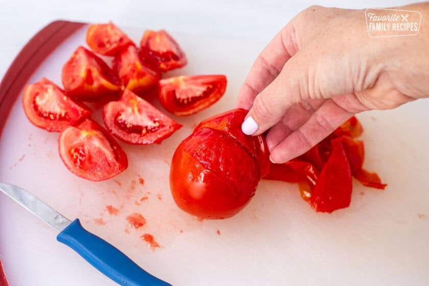 Peeling skin from blanched tomatoes.