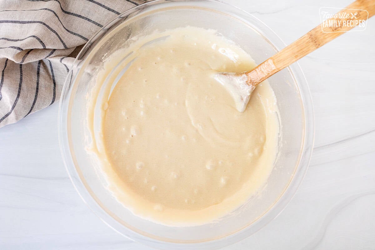 Melted brown sugar, butter and marshmallow in a glass bowl with a wooden spoon spoon.