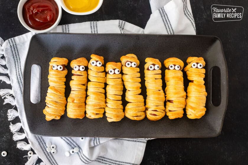 Mummy hot dogs lined in a row with sprinkle eyeballs.