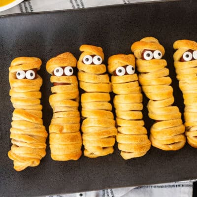 Mummy hot dogs lined in a row with sprinkle eyeballs.