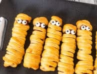 Mummy hot dogs lined in a row with candy eyeballs.