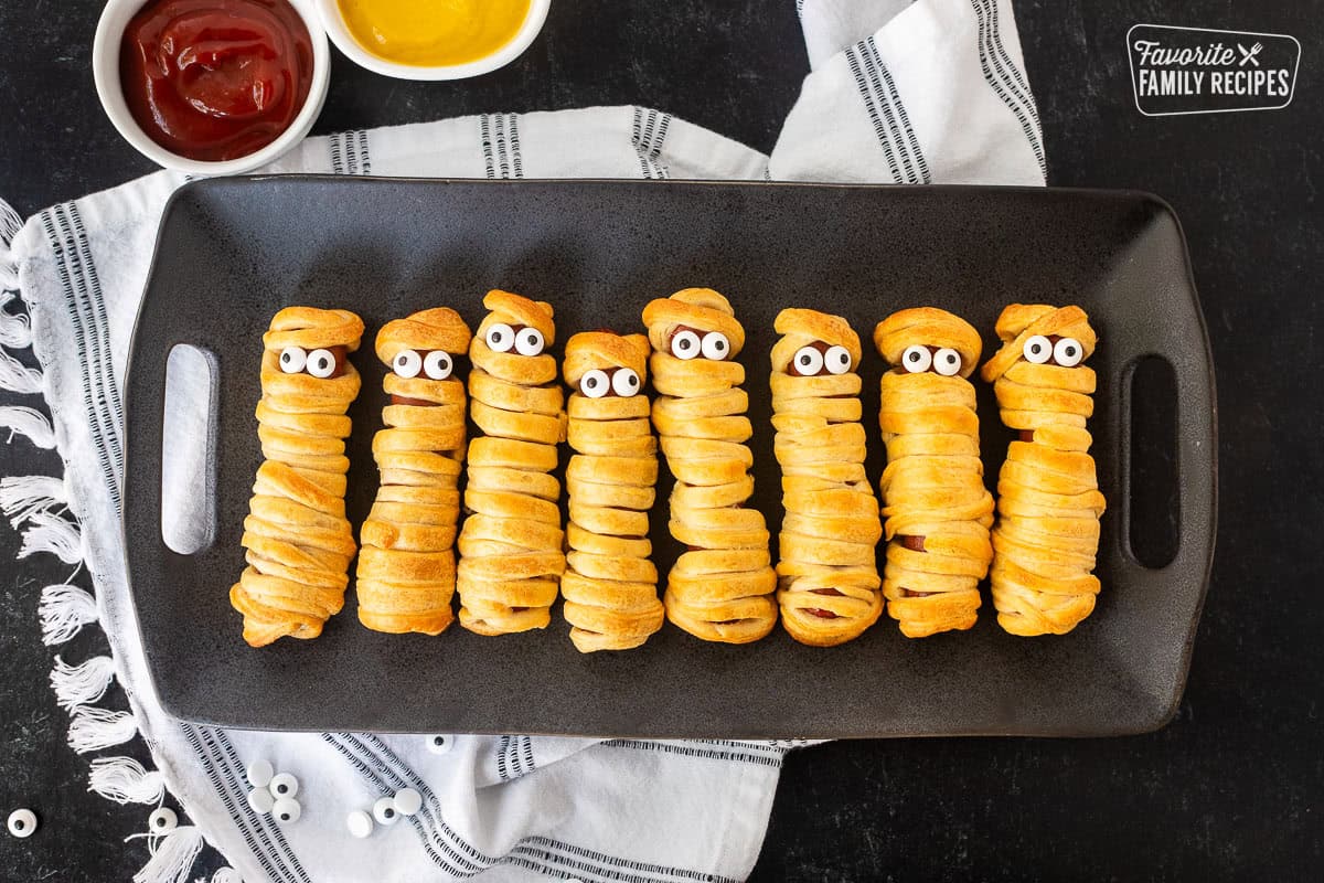 Mummy hot dogs lined in a row with sprinkle eyeballs.