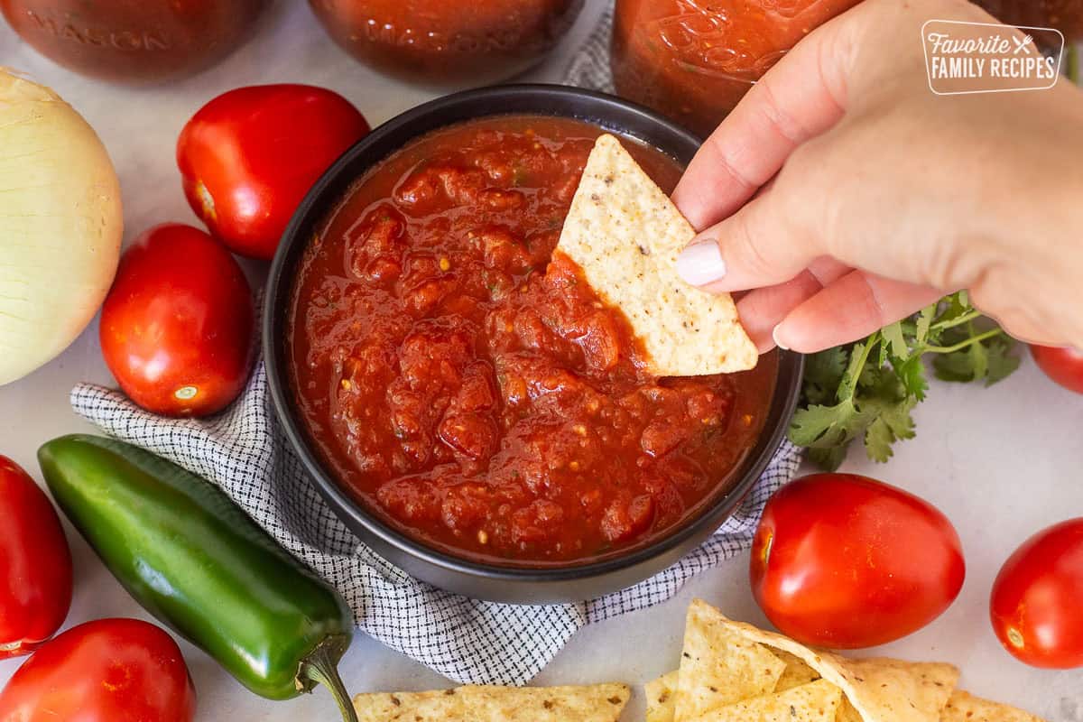Chip dipping into a bowl of savory canned salsa.