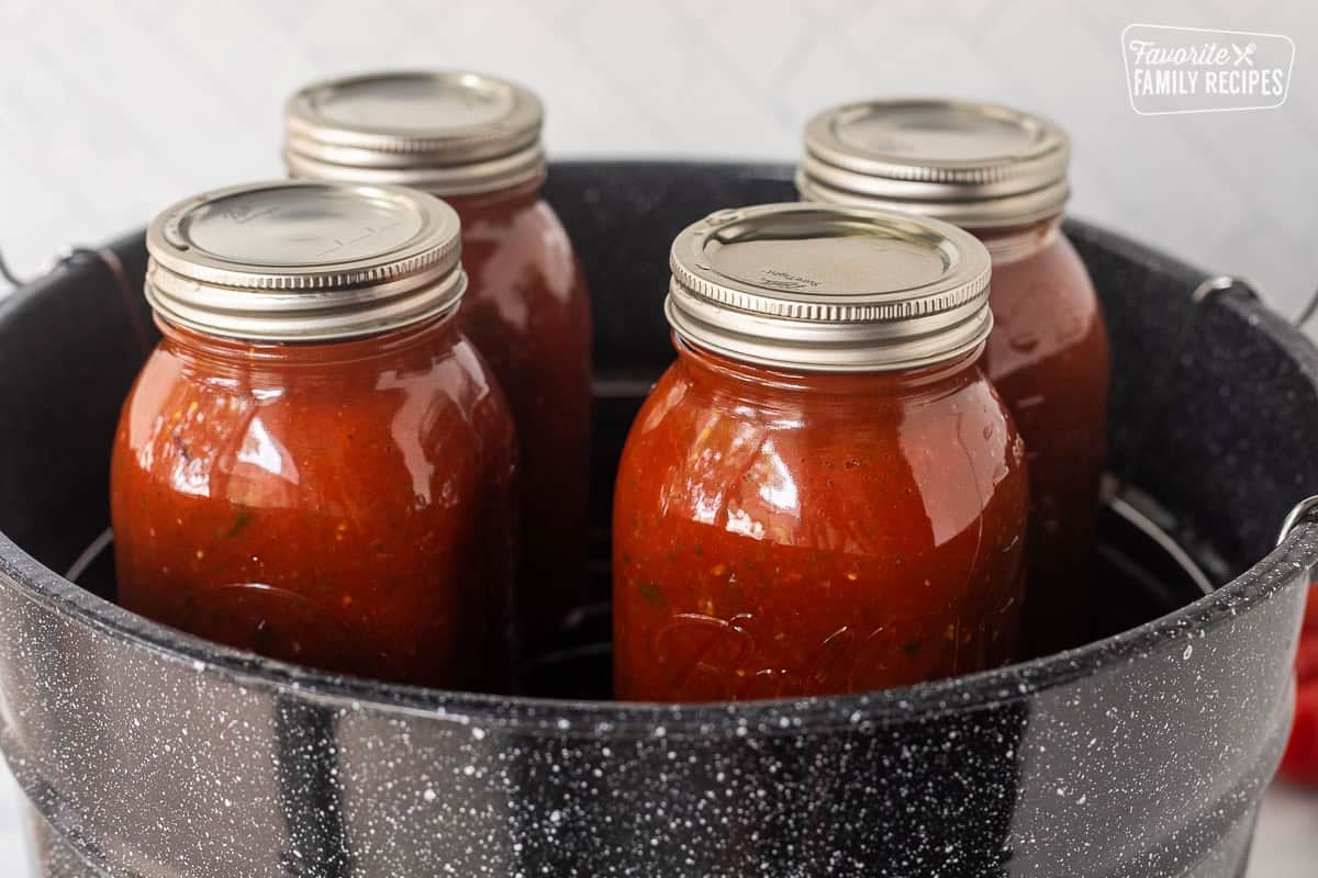 Canning pot with four jars of savory canned salsa.