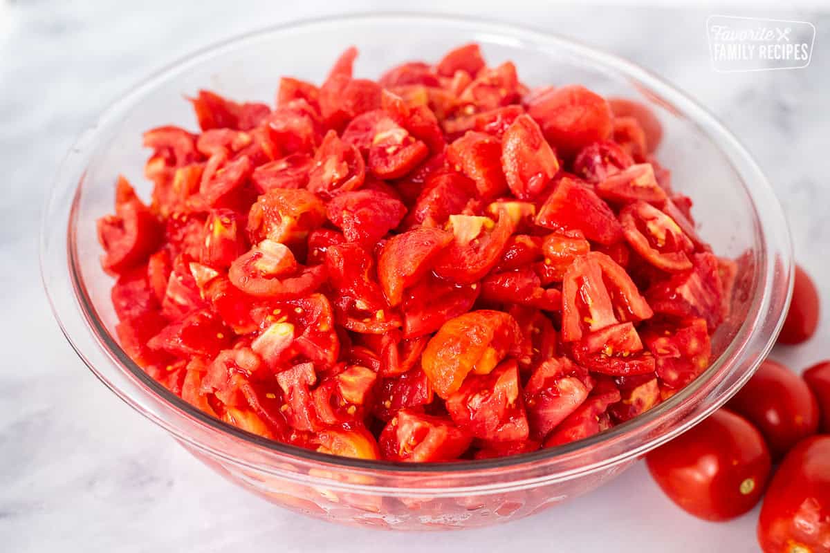 Large glass bowl with peeled and diced tomatoes.
