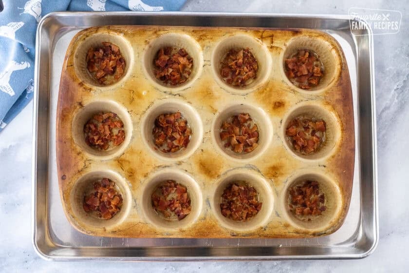 Bacon pieces added to bottom of muffin pan.