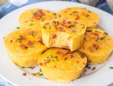 Starbucks egg bites on a plate with a bite taken out of it and garnished with bacon and chives.