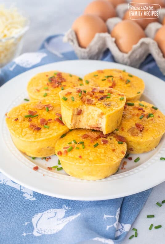 Starbucks egg bites on a plate with a bite taken out of it and garnished with bacon and chives.