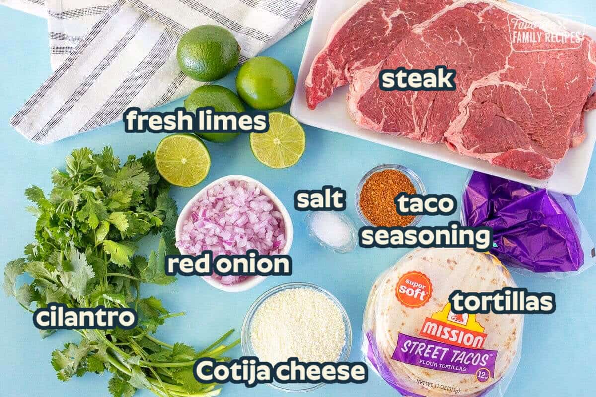 Ingredients to make Street Tacos including steak, limes, tortillas, cilantro, red onion, salt, seasoning and cheese.