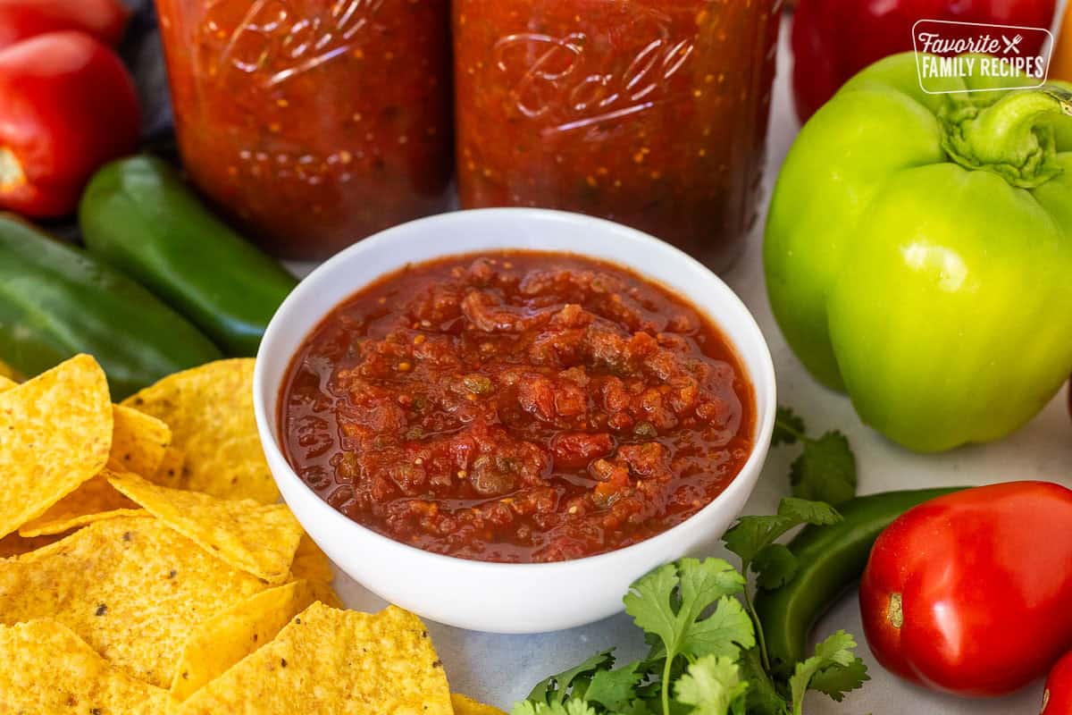 Sweet canned salsa and a bowl next to jars of salsa and chips.