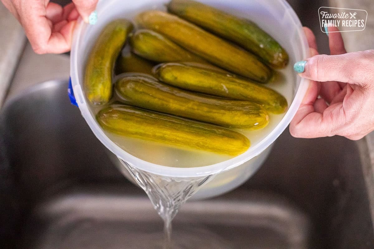 Pouring out salted water from cucumber container.