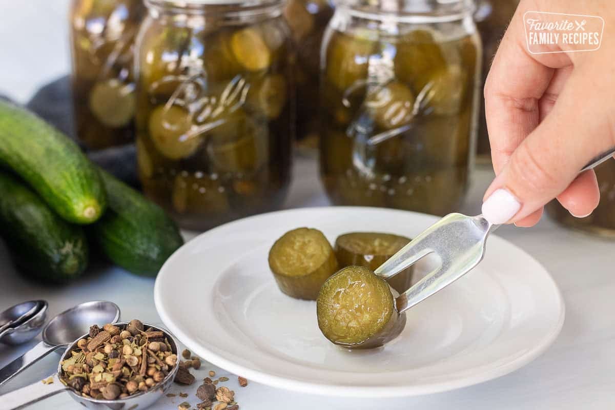 Stabbing a sweet pickle with a fork on a plate.