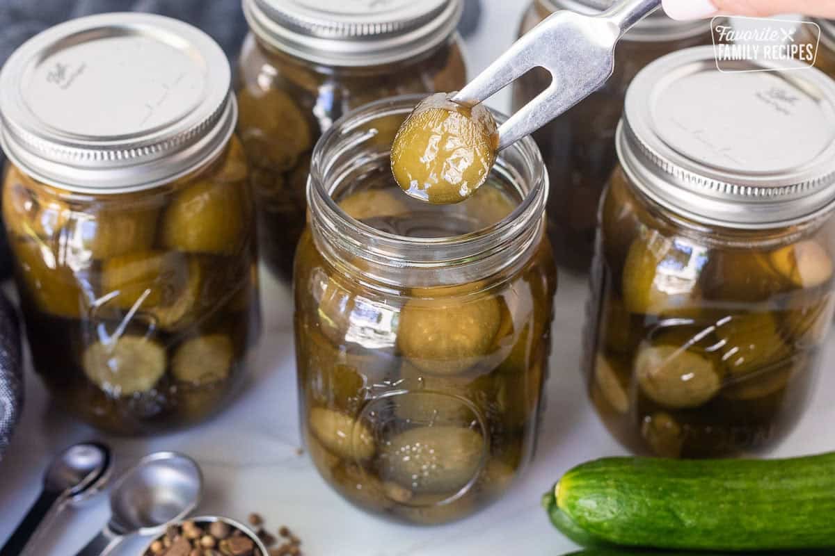 Stabbing a sweet pickle with a fork out of a canning jar.