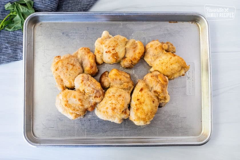 Golden brown chicken thighs on a sheet pan.