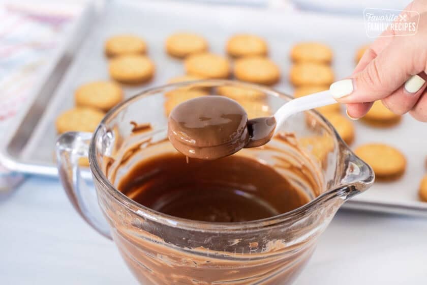 Lifting covered Ritz sandwich crackers covered in milk chocolate lifted with plastic fork.