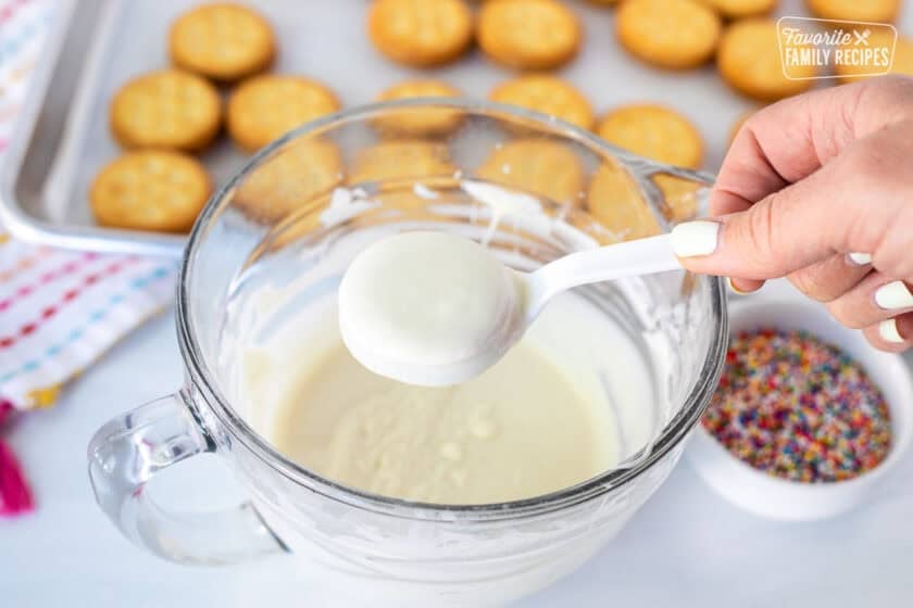 Lifting covered Ritz sandwich crackers covered in white chocolate lifted with plastic fork.