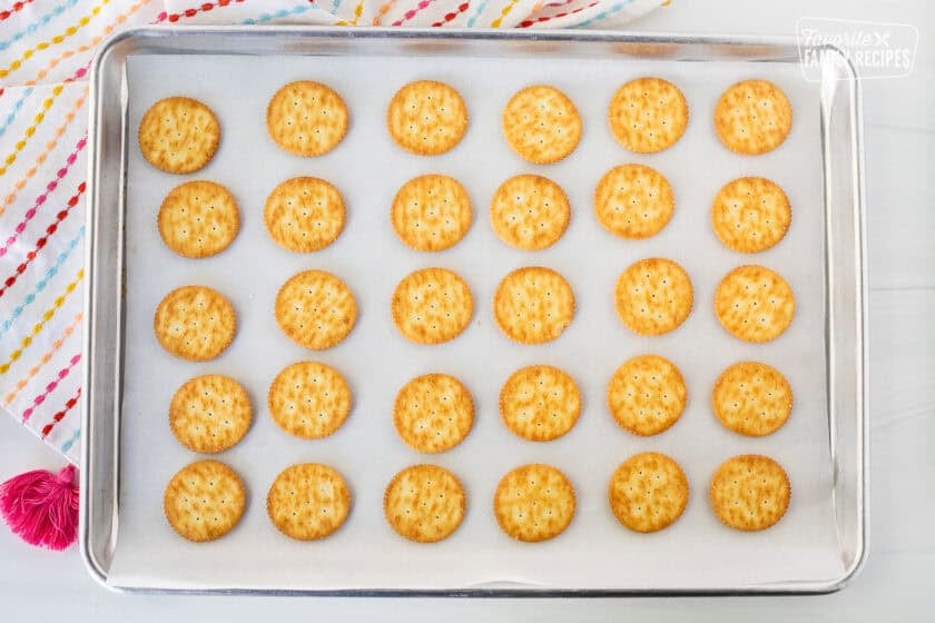 Ritz crackers lined up on parchment paper.
