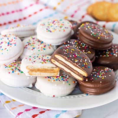 Cut white chocolate peanut butter filled and milk chocolate Rolo filled Ritz crackers with multi colored sprinkles on a plate.