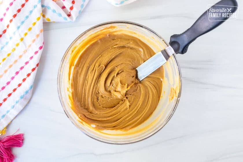 Glass bowl with peanut butter combined with powdered sugar.