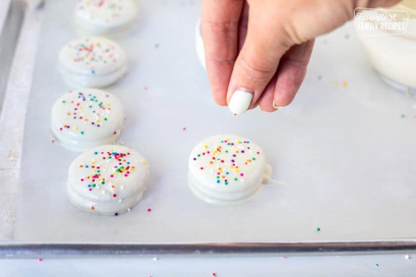Placing sprinkles on top of white chocolate covered ritz crackers.