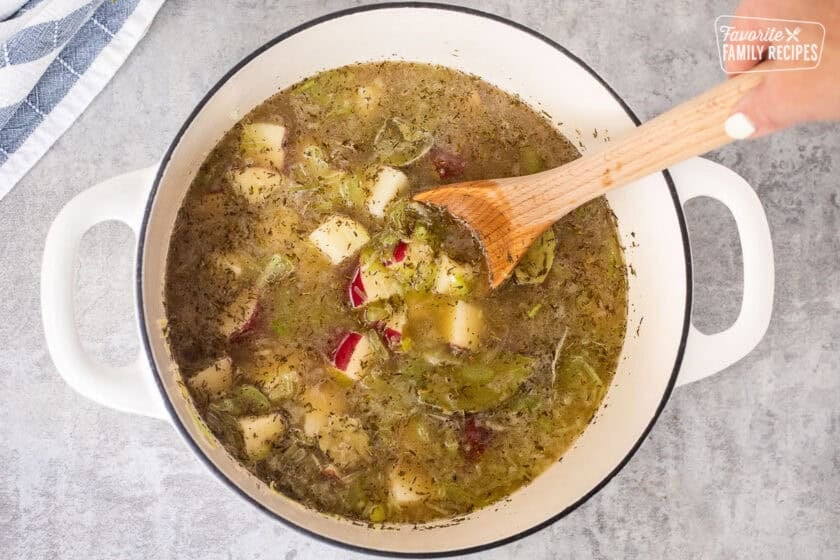 Stirring in chicken broth and red potatoes into dutch over with sautéed vegetables.