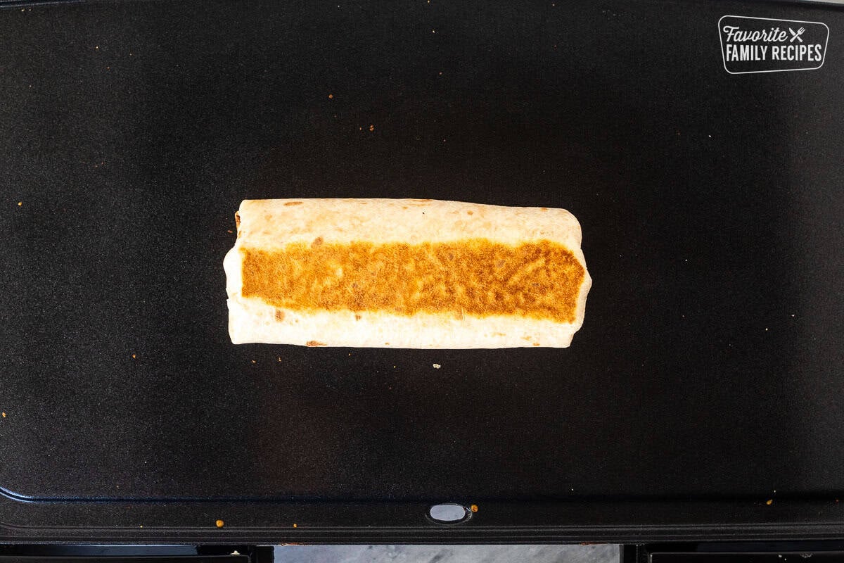 Rolled up browned quesarito on a skillet.