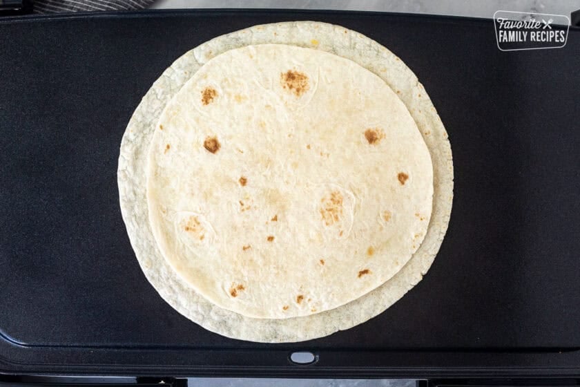 Skillet with tortilla topped with cheese and second tortilla.
