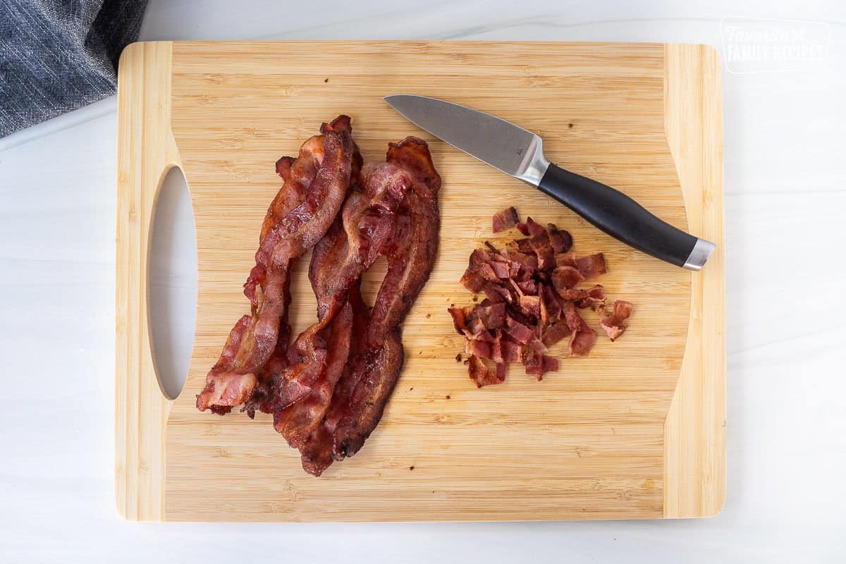 Slices of bacon on a cutting board being cut to make bacon bits for corn chowder