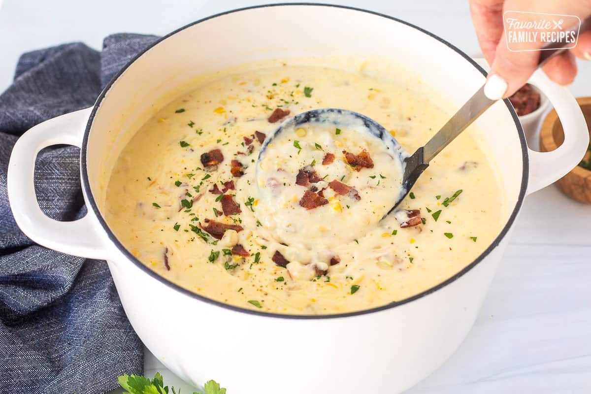 A large pot of corn chowder with a ladle dipped in to serve