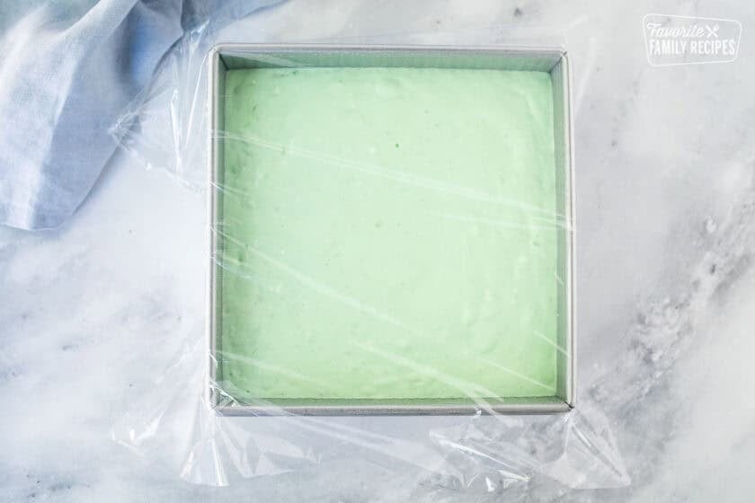 Pan with lime jello salad mixture covered with plastic wrap.