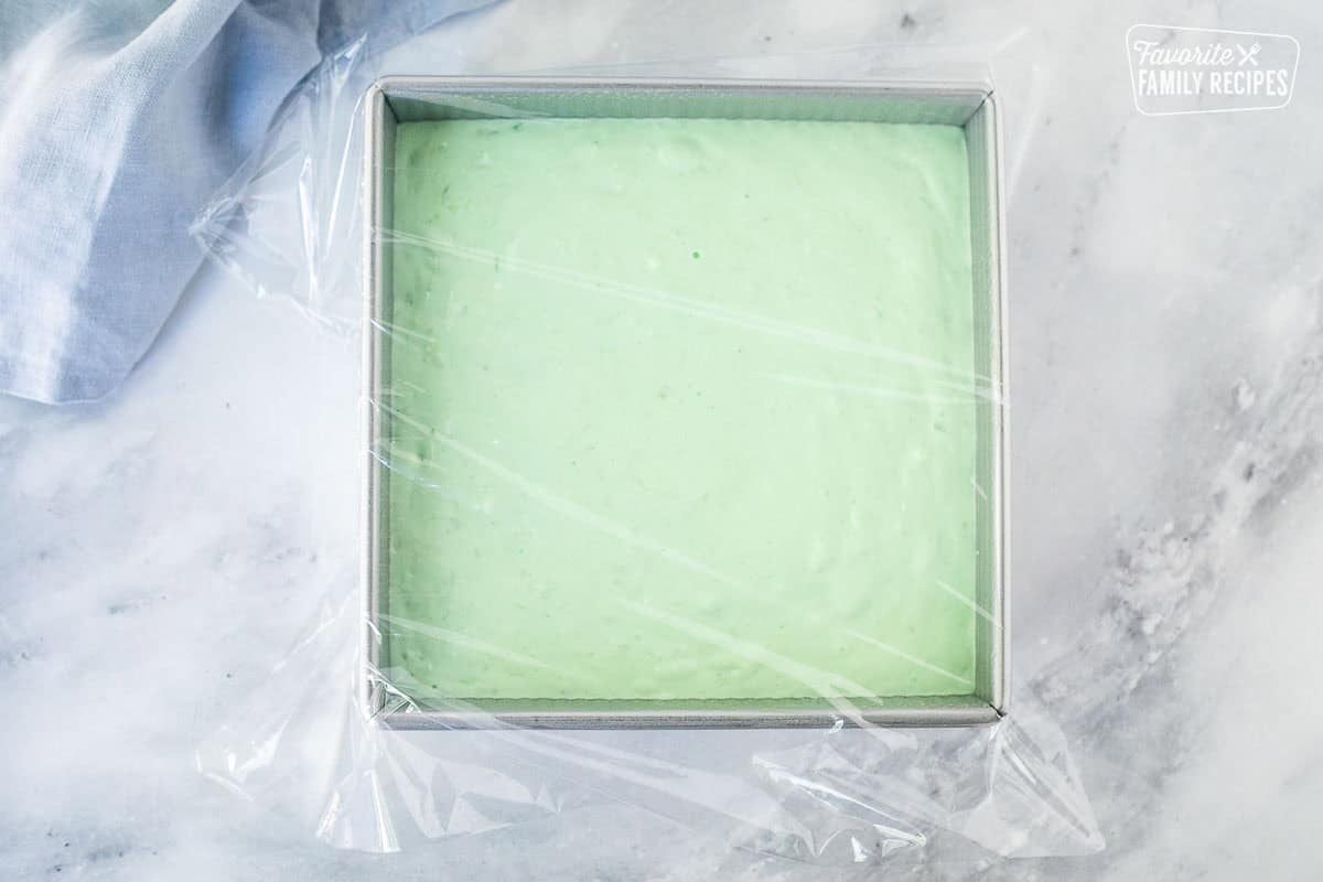 Pan with lime jello salad mixture covered with plastic wrap.