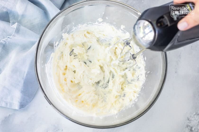 Whipping cream cheese in a large mixing bowl with electric beaters.