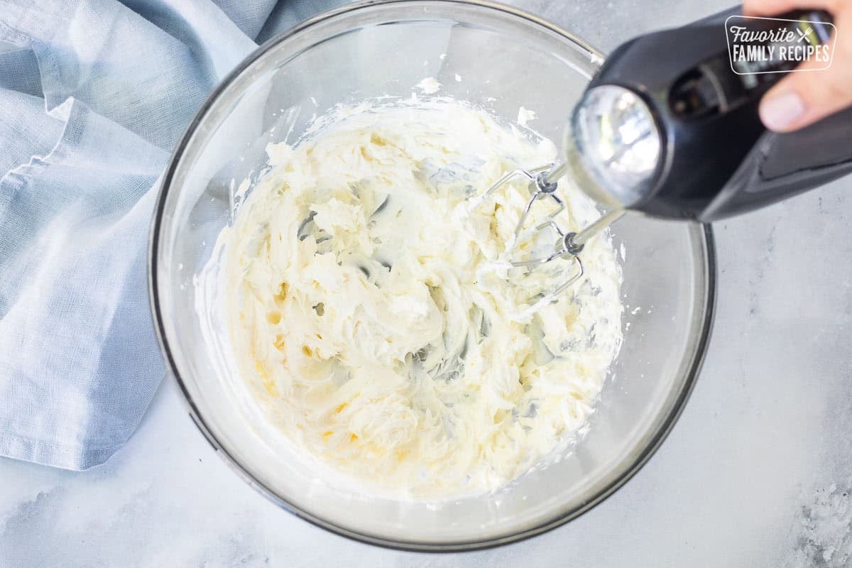 Whipping cream cheese in a large mixing bowl with electric beaters.