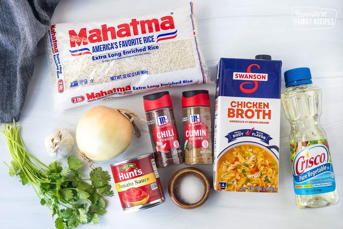 Ingredients to make Mexican Rice including rice, chicken broth, vegetable oil, cumin, chili, salt, tomato sauce, onion, garlic and cilantro.