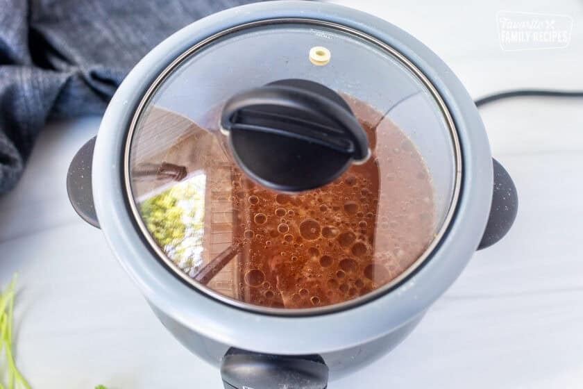 Placing a lid on a rice cooker cooking Mexican rice.