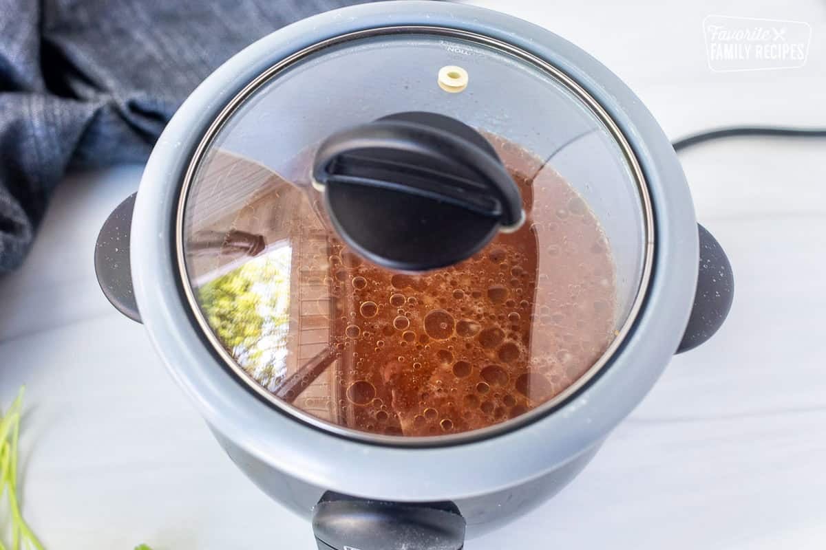 Placing a lid on a rice cooker cooking Mexican rice.