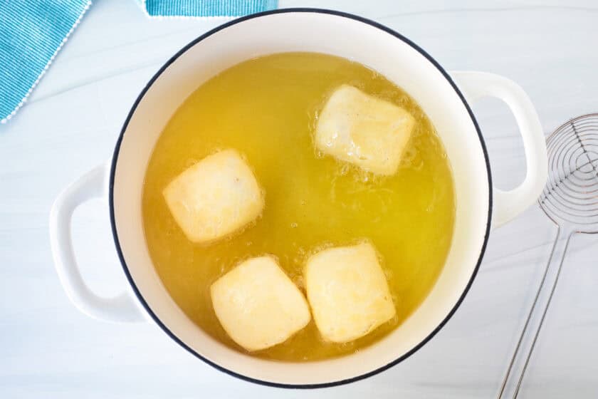 For New Orleans style beignets cooking in a pot of hot oil.