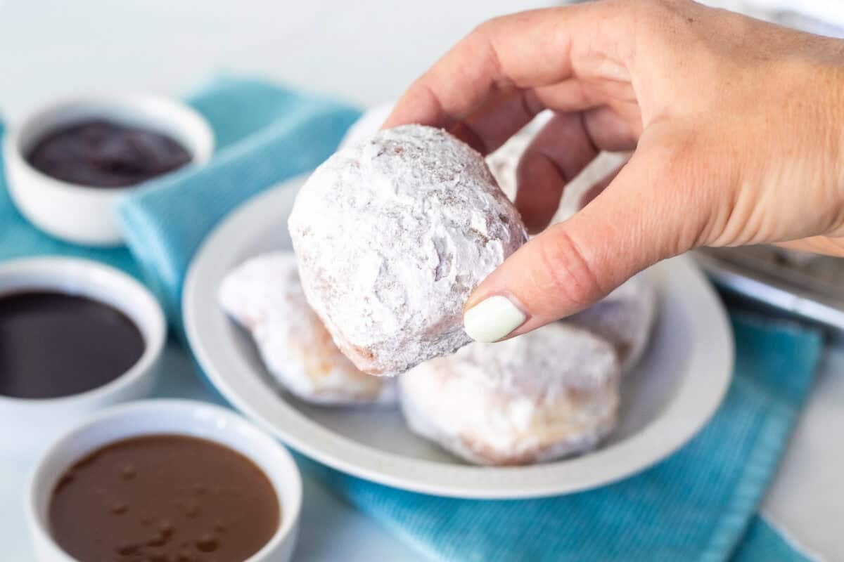 Holding a new Orleans style beignet over caramel dipping sauce.