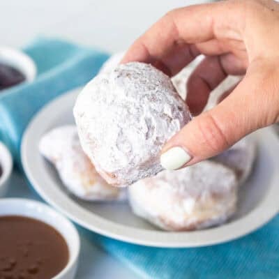 Holding a new Orleans style beignet over caramel dipping sauce.