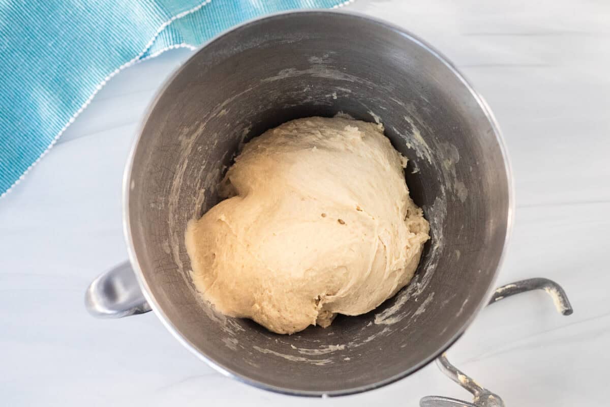Mixing bowl with kneaded dough and a dough hook on the side.