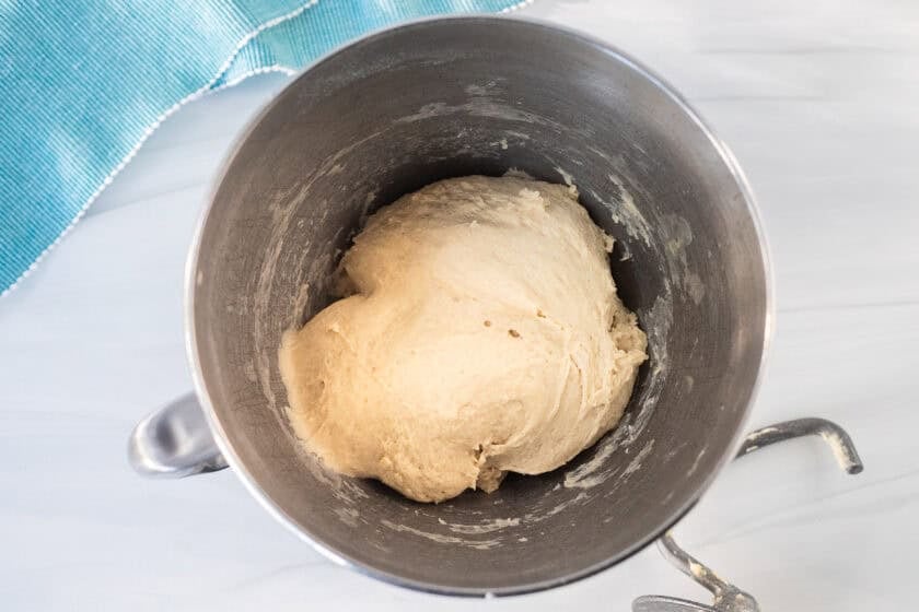 Mixing bowl with kneaded dough and a dough hook on the side.