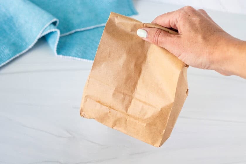 Hand holding a paper bag that has been folded over.