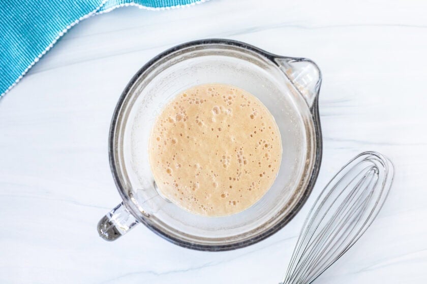 Glass bowl with yeast, sugar and warm water. Whisk on the side.
