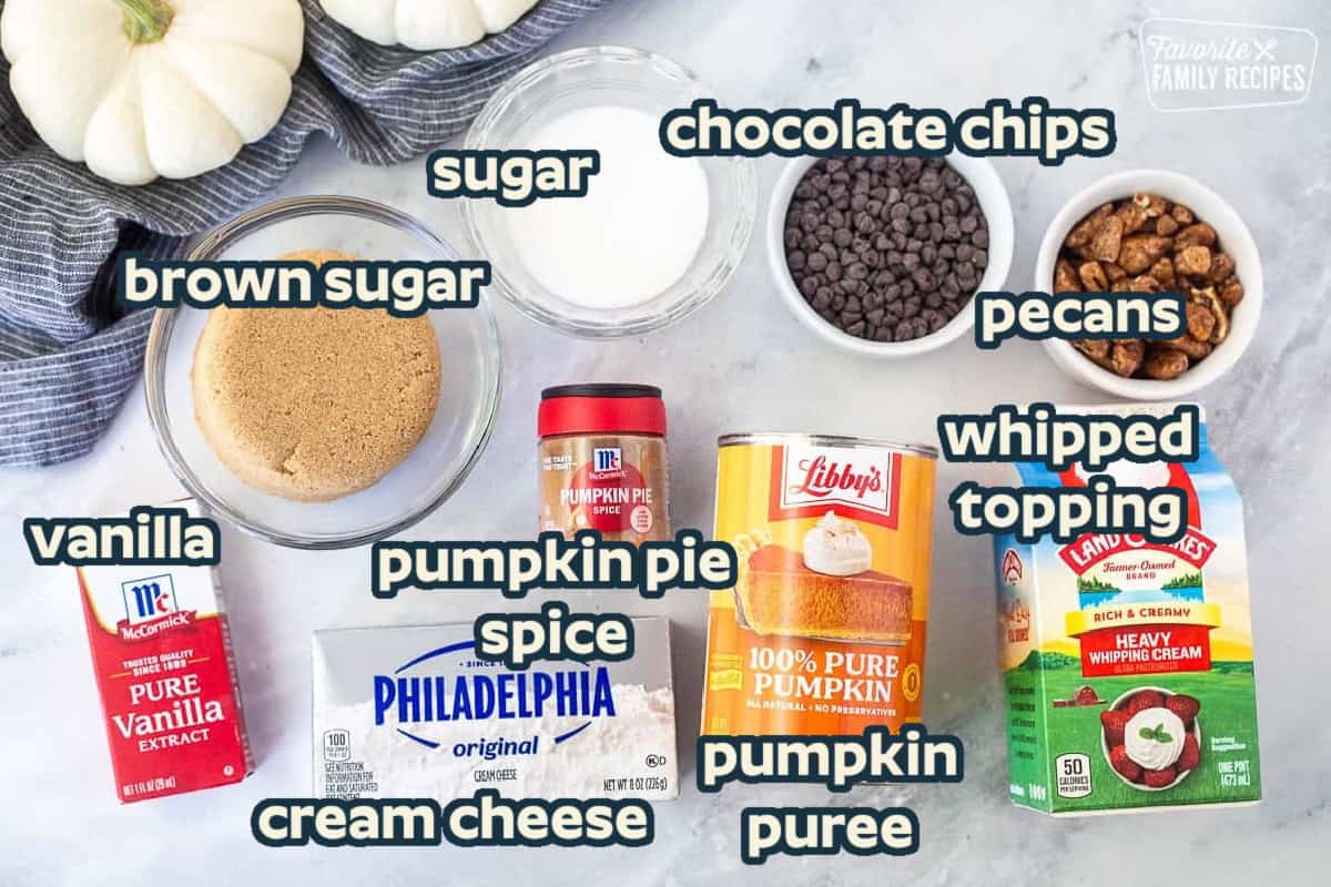 Ingredients to make pumpkin mousse including heavy whipping cream, pure pumpkin, cream cheese, vanilla, pumpkin pie spice, brown sugar, sugar, mini chocolate chips and candied pecans.
