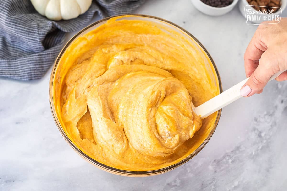 Glass bowl of pumpkin mousse base combining with whipping cream.
